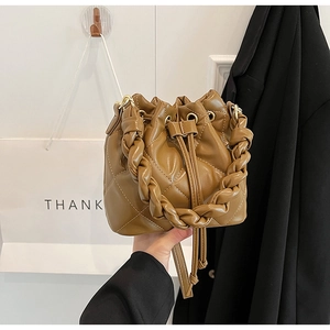 Close-up of brown quilted leather bucket bag with drawstring and woven handle