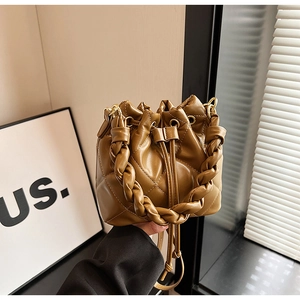 Detailed view of brown quilted bucket bag with braided handle and gold metal hardware