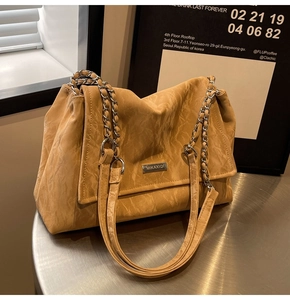 Detailed view of dark mustard yellow tote bag with silver chain strap and metal logo
