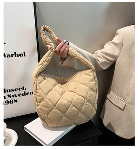 Detail of beige quilted nylon handbag featuring heart stitching and silver zipper closure