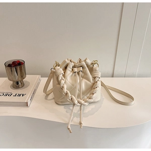 Detail of cream bucket bag showing quilted leather texture and woven handle