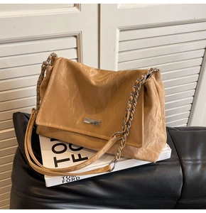 Macro detail of khaki wrinkled leather texture and metallic chain strap on tote bag