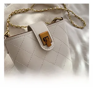 Detailed close-up of golden metal twist lock on cream-white quilted mini bucket bag