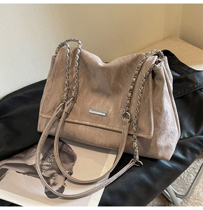 Detailed view of dust pink tote bag featuring a textured leather finish and metal logo