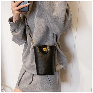 Close-up of a black quilted bucket bag with a gold twist-lock and woven chain strap