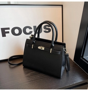 Detail of black lychee grain tote bag with gold metal clasp and adjustable shoulder strap