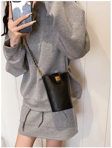 Detail of quilted leather bucket bag with gold chain strap and metal turn-lock closure