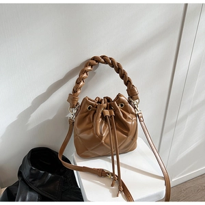 Close-up of brown quilted leather bucket bag featuring a woven handle and drawstring detail
