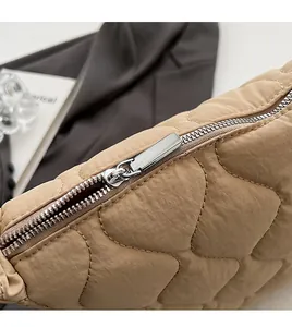 Close-up of smooth silver metal zipper and quilted khaki nylon texture on tote bag