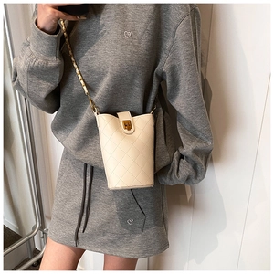 Detail of quilted beige bucket bag with gold chain strap and metallic twist lock