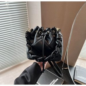 Detailed shot of black quilted bucket bag featuring woven handle and drawstring closure