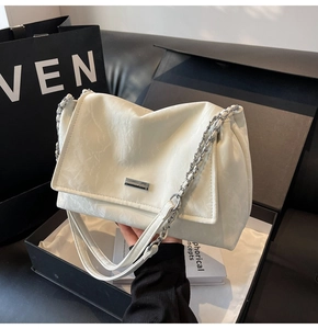 Detail of off-white pleated tote bag with silver chain strap and metal logo plate