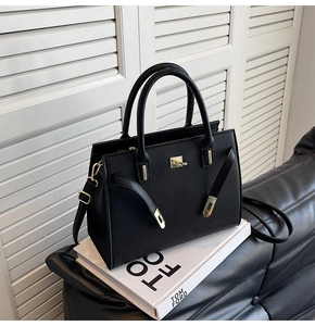 Elegant black lychee leather handbag with gold hardware displayed on fashion books
