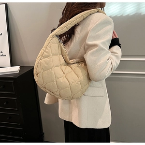 Beige quilted nylon crescent shoulder bag shown on model with chic cream blazer