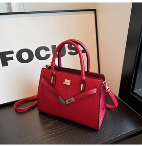 Detail of red bridal handbag with cross-grain texture, gold twist lock and V-strap design