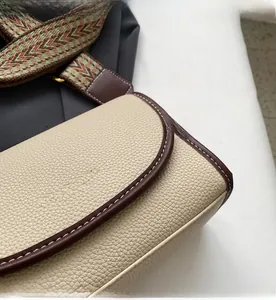 Détails du cuir grainé beige et de la bandoulière tissée pour ce sac à bandoulière chic