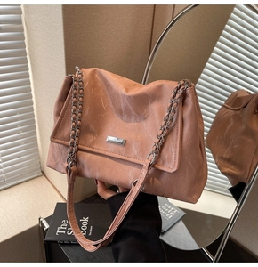 Detail of pink marble pattern tote bag with silver chain strap and metallic brand plate