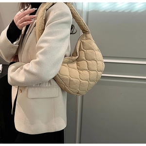 Detail of a beige quilted crescent shoulder bag showing the nylon fabric and stitching