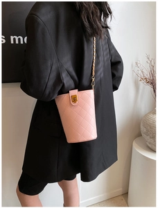 Detailed back view of pink quilted bucket bag with gold chain strap on black blazer