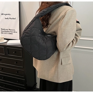 Detail of a black quilted tote bag showing texture and reinforced shoulder strap padding