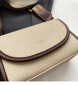Détail de sac bandoulière en cuir beige avec bordure marron et surpiqûres blanches