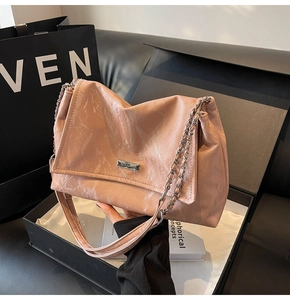 Detail of pink marble pattern tote bag with silver chain strap and metal logo plaque