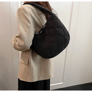 Close-up of quilted black nylon tote bag showing padded texture and shoulder strap fit