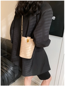 Close-up of beige quilted leather crossbody bag with gold chain strap on a model