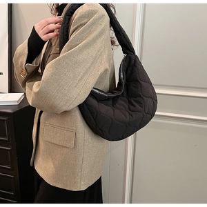 Close-up of black quilted nylon hobo bag with diamond pattern and silver zipper