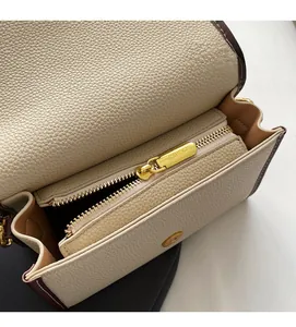 Gros plan sur le compartiment zippé intérieur et la texture en cuir du sac à bandoulière