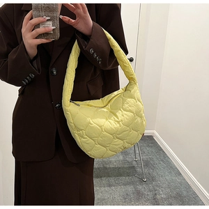 Quilted crescent shoulder bag in soft yellow, worn over a brown blazer for style