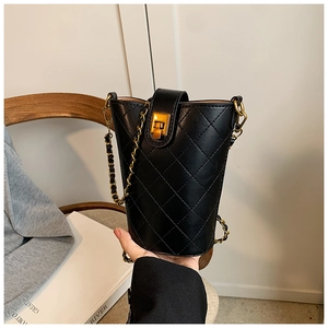 Detailed close-up of black quilted bucket bag with gold chain and vintage metal lock
