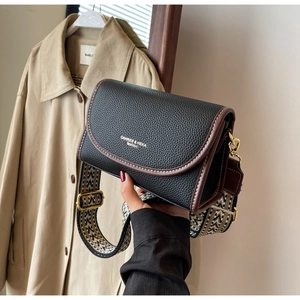 Détail du sac à main en cuir grainé noir avec bordure marron et bandoulière tissée