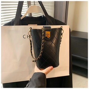 Close-up of quilted black leather bucket bag with gold chain strap and turn-lock detail