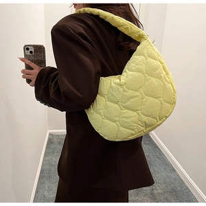 Close-up of a light yellow quilted nylon tote bag with wave-pattern stitching details