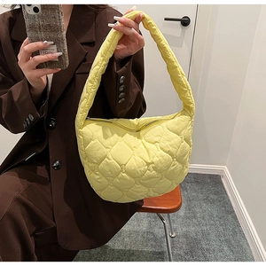 Close-up of bright yellow quilted nylon tote bag with crescent shape and metal zipper