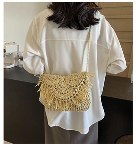 Detail of bohemian straw crossbody bag with fringe tassels and woven texture