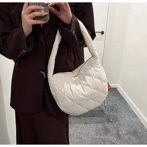 Close-up of white quilted nylon hobo shoulder bag with crescent shape and zip closure