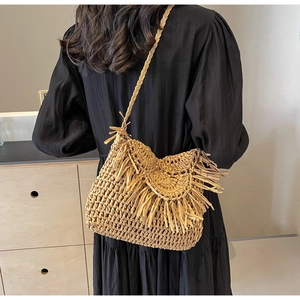 Detailed shot of handmade straw crossbody bag featuring long fringe and honeycomb texture
