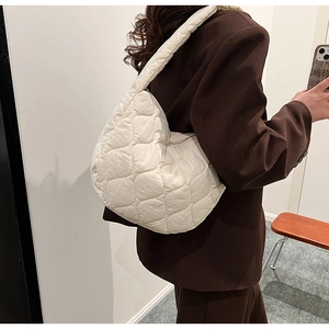 Detailed view of white quilted nylon tote bag with cloud texture on a female model