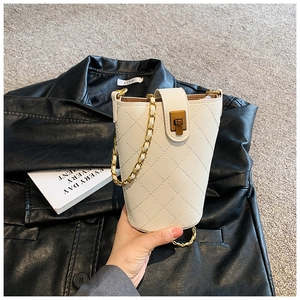 Detail of cream quilted leather bucket bag with gold chain strap and turn-lock closure