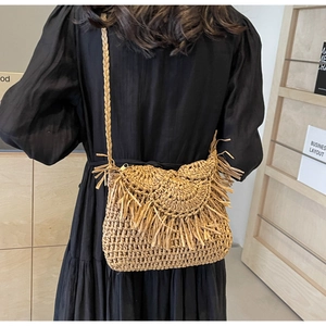 Detail of hand-woven straw bag featuring decorative long tassels and crochet wave texture