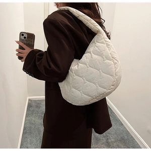 Close-up of a white quilted crescent shoulder bag made of soft and lightweight nylon fabric