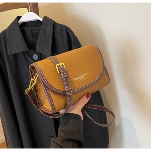 Détail du sac à main en cuir jaune moutarde avec bordure marron et boucles dorées