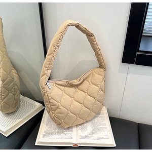 Close-up of beige quilted nylon hobo bag with wavy stitching and metal zipper detail