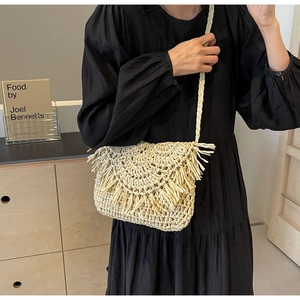Detail of handmade cream straw crossbody bag featuring fringe trim and woven strap