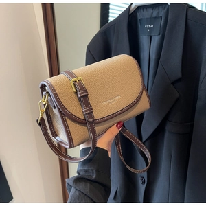 Gros plan d'un sac bandoulière en cuir marron vintage avec texture litchi et boucle dorée