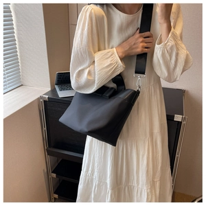 Close-up of black nylon bucket bag with bow detail and wide shoulder strap on model