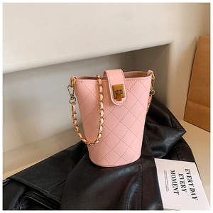 Close-up of pink quilted bucket bag with golden chain strap on a black leather jacket