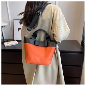 Detail of orange nylon bucket bag with black bow and detachable wide crossbody strap